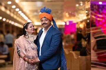 A middle-aged couple in traditional Indian attire smiling and posing together.