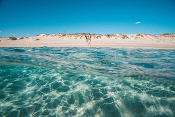 Couple enjoying a sunny day at a pristine beach with clear turquoise water.