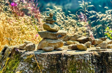 Balanced stones on a tree stump in a sunny field.