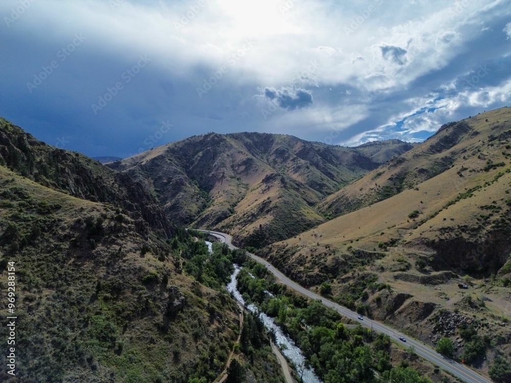 Sticker Aerial view of a river winding through mountains under a dramatic sky.