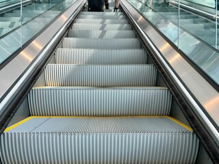 Close-up view of an empty escalator in modern CVG Airport building with glass railings, shadows