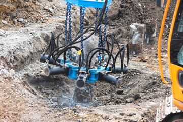 Builders using hydraulic pile cropper excavator attachment to cut off top of pile at a Construction...