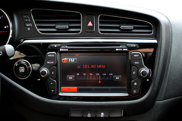 Monitor on dashboard of car in FM receiver. Controlling volume in car. Modern car multimedia. Detail of the car interior. 