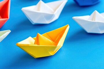 Leadership Concept with Paper Boats. Set of colorful origami ships on blue background. Business competition, Leadership concept with yellow paper ship leading among white with generative ai