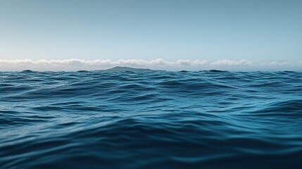 A calm ocean with gentle waves and a distant island on the horizon