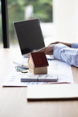 Fototapeta premium Businessman working in real estate Tuff and his laptop run a simple calculator. With various house models