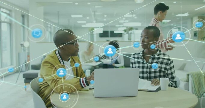 Animation of network of connections with icons over diverse colleagues using laptop in office