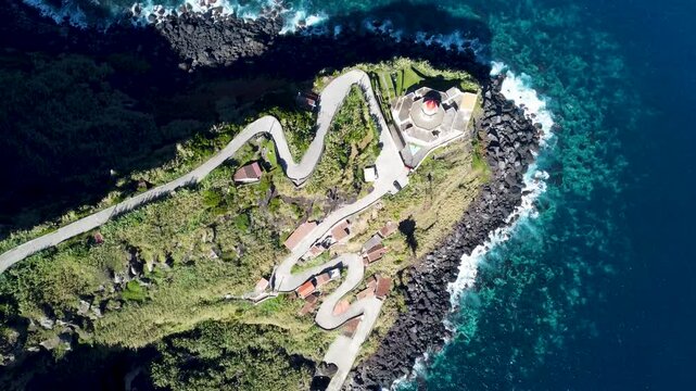 Aerial footage of the Arnel Point Lighthouse, on a sunny day in Sao Miguel island, Azores, Portugal
