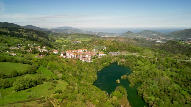 green landscape with hills, houses and small lake at Trapaga-Trapagaran Valley in Spain