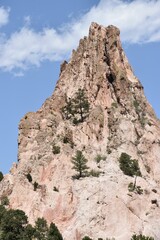 Rocky mountain peak with sparse trees under a clear blue sky.