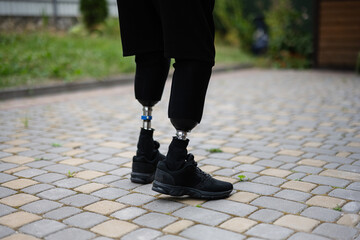 Person with prosthetic legs standing on paved pathway outdoors