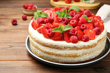 Tasty sponge cake with fresh berries and mint on wooden table, closeup