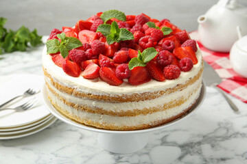 Tasty sponge cake with fresh berries and mint on white marble table, closeup