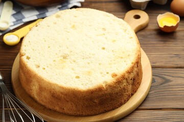 Tasty cut sponge cake and ingredients on wooden table