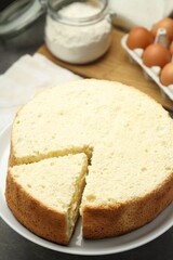 Tasty cut sponge cake on grey table