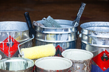 Empty paint buckets containing used rollers and brushes.