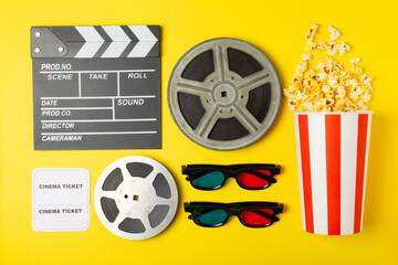 Tasty popcorn in buckets and cold cola drinks with cinema tickets, movie clapper and 3D eyeglasses...
