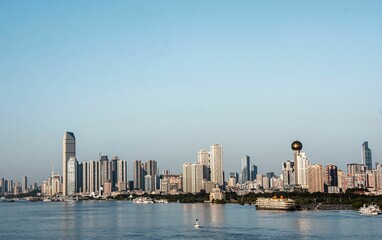 Modern city skyline with river and clear blue sky.