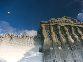 Abstract reflection of town in water. Cityscape. Abstract distorted classical building with pillars...