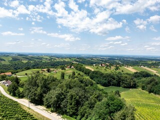 View of a lush, green landscape with rolling hills, scattered houses, and a clear blue sky