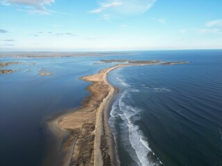 Aerial view of a sandy beach between a bay and the ocean.