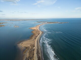 Aerial view of a sandy coastline with waves and a blue sky