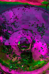 Backdrop with top view of abstract vivid green and purple inky circles placed on blurred multicolored transparent surface. Futuristic abstract vertical background.