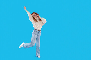 Joyful Young Woman Celebrating Against a Bright Blue Background With Style and Enthusiasm