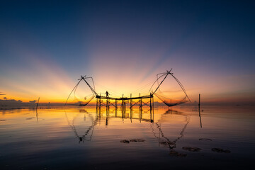 Fishermen scoop up fish in a giant squa dip net in Songkhla Lake with twilight in the morning at Ban Pak Pra, Phatthalung.