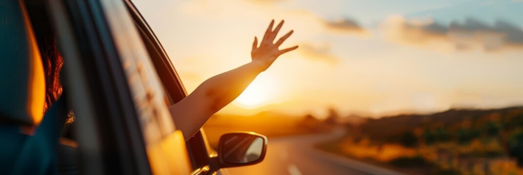 Woman's hand reaching out of car window at sunset.