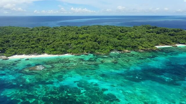 Drone scenery of green island surrounded by turquoise waters on a sunny day with blue bright sky