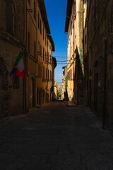 Narrow street in an Italian town with clear blue sky.