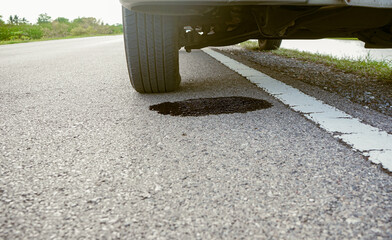 Dirty engine oil stains from a car leaking under a broken car on the road. Old engine oil stains on the road Car repair and maintenance concept