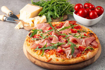 Pizza with prosciutto, ham, arugula, spinach, tomatoes, pesto, cheese and parmesan. Italian cuisine. 
