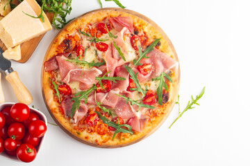 Pizza with prosciutto, ham, arugula, spinach, tomatoes, pesto, cheese and parmesan. Italian cuisine. 