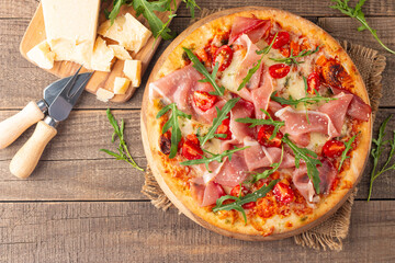 Pizza with prosciutto, ham, arugula, spinach, tomatoes, pesto, cheese and parmesan. Italian cuisine. 