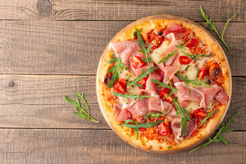 Pizza with prosciutto, ham, arugula, spinach, tomatoes, pesto, cheese and parmesan. Italian cuisine. 