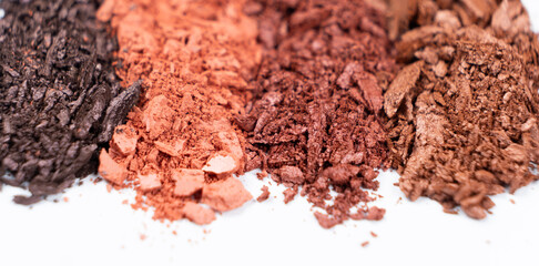 Scattered eye shadows in different shades. Cosmetics texture, white background.