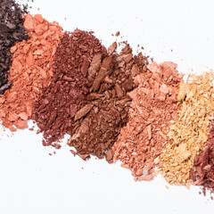 Scattered eye shadows in different shades. Cosmetics texture, white background.