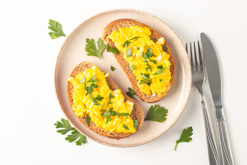 Scrambled eggs with green herbs on wheat-rye crispy toast.