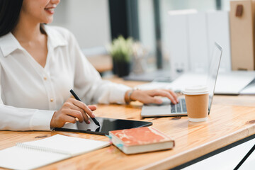 Efficient woman working on tablet and laptop at modern workspace