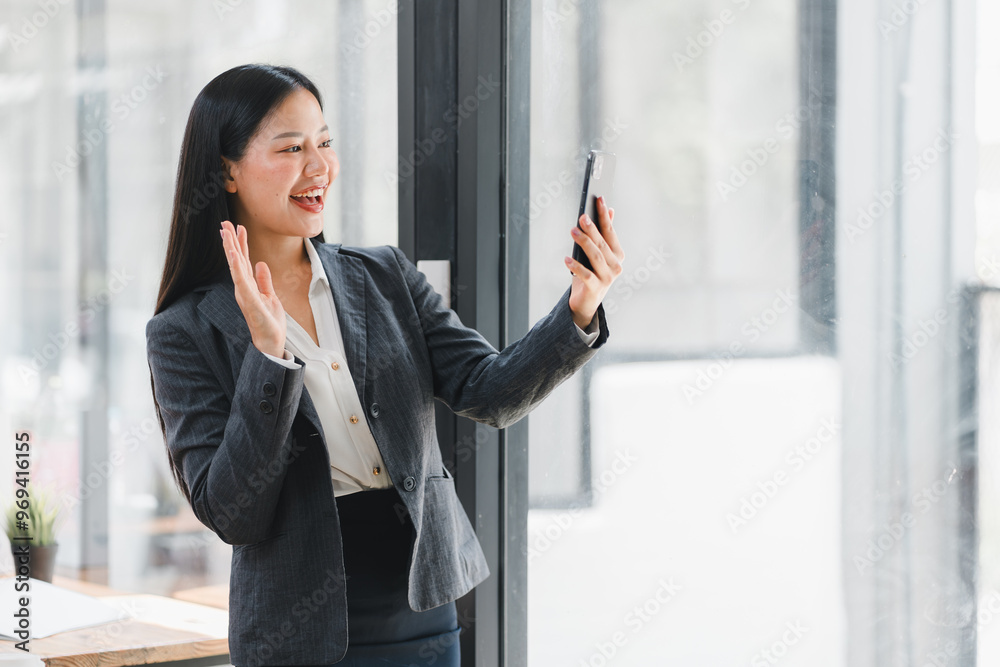 Wall mural a businesswoman happily video calling in modern office setting