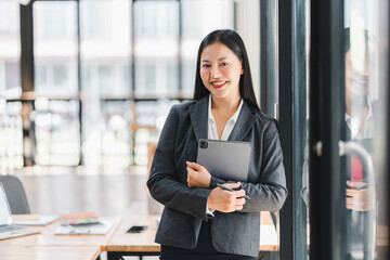 Professional woman in suit holding tablet, smiling confidently in an office