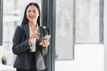 Professional woman smiling, using smartphone in modern office