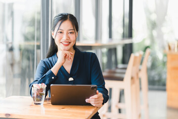 A confident woman smiles while using tablet in cozy cafe setting