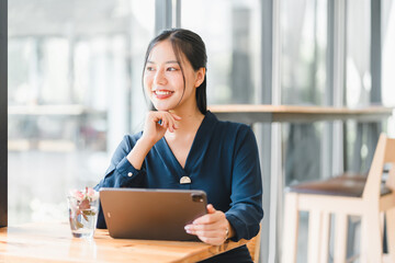 A confident woman smiles while using tablet in modern cafe