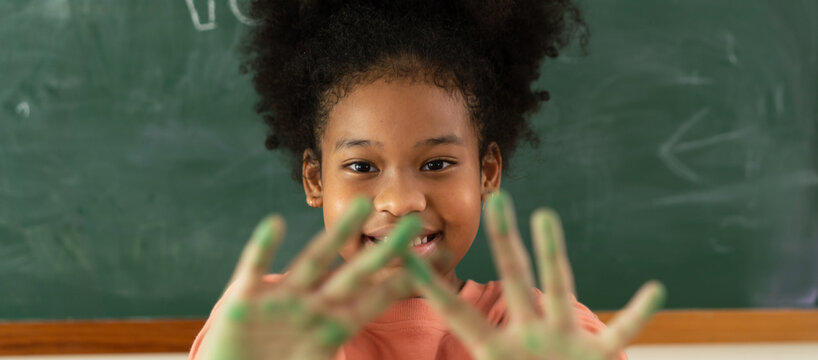 Smiling African American Girl in Classroom with Green Paint on Hands, Embracing Creativity and Joy in Art Class