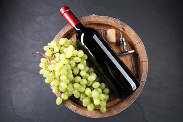 Obraz premium Corkscrew with metal handle, bottle of wine, grapes, cork and wooden barrel on grey table, top view