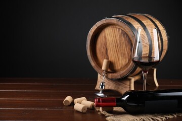 Corkscrew with metal handle, corks, bottle of wine, glass and barrel on wooden table, space for text