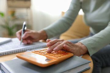 Budget planning. Woman using calculator while working with accounting documents at table indoors, closeup